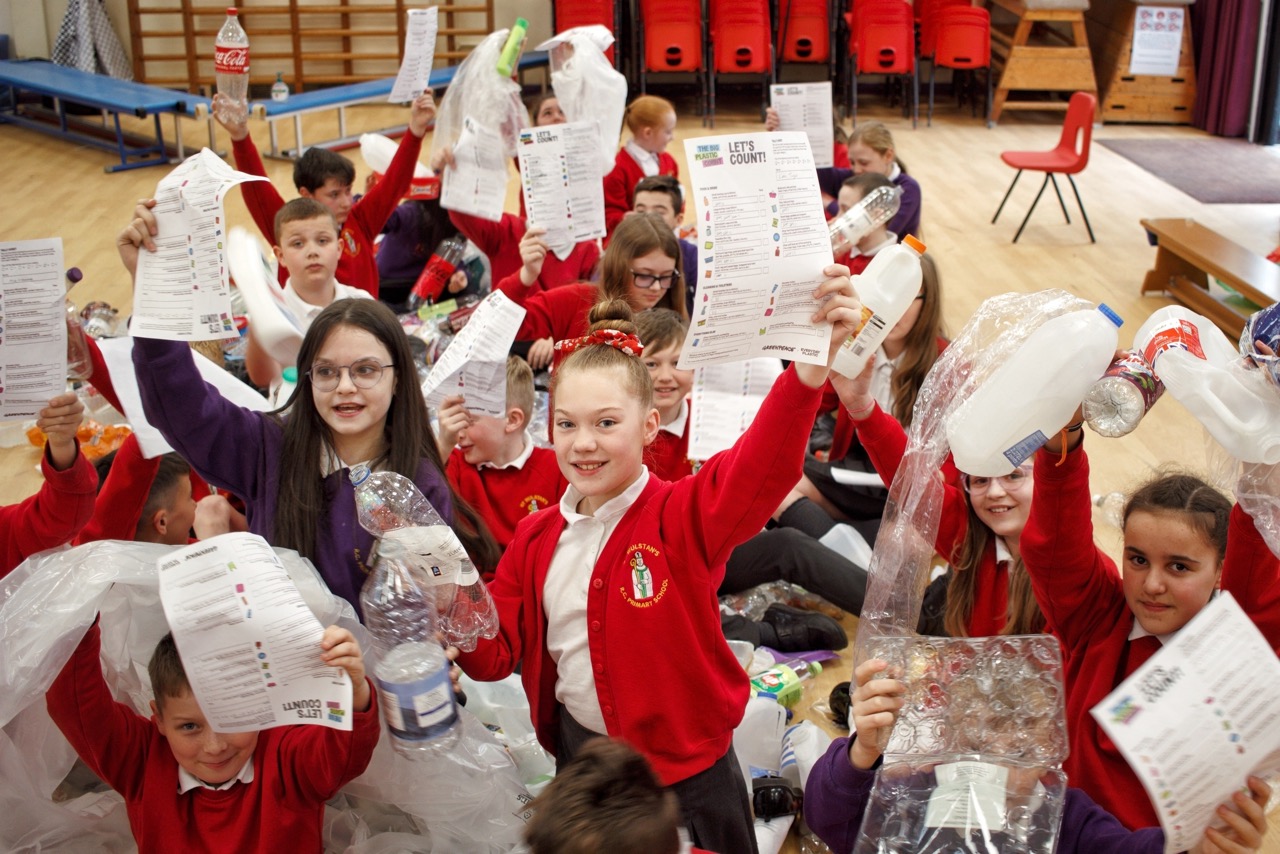 A group of children hold up The Big Plastic Count count sheets