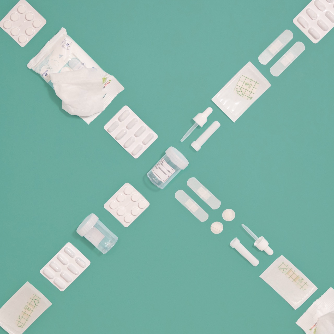 Different forms of medical-related, white plastic form a cross or an X on a teal background